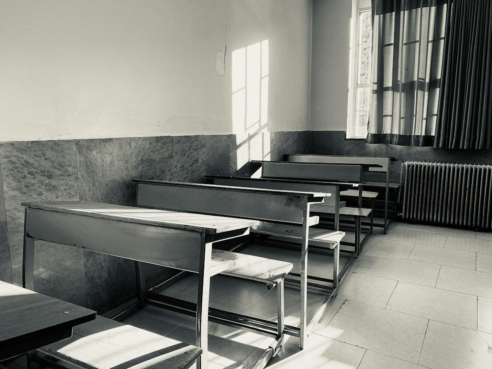 Black-and-white photo of empty school desks in window light